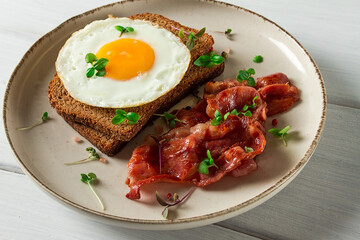 Breakfast, fried egg with bacon, micro-green, on a light background, no people, selective focus,