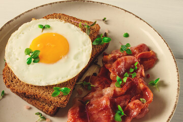 Breakfast, fried egg with bacon, micro-green, on a light background, no people, selective focus,