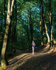 Fototapeta na wymiar Young travel woman with backpack exploring woods in mountains in the morning