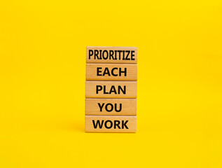 Naklejka premium Priority, plan and work symbol. Wooden blocks with words Prioritize each plan you work. Beautiful yellow background. Business and Prioritize each plan you work concept. Copy space