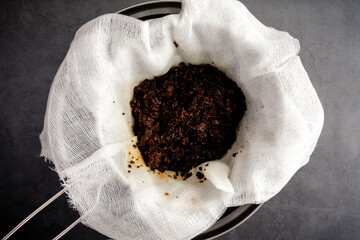 Used Coffee Grounds in a Cheesecloth Lined Strainer: Coffee grounds leftover after straining cold...