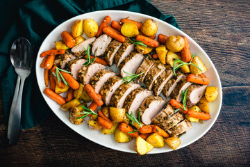 Roast Pork Tenderloin with Potatoes and Baby Carrots: Sliced pork medallions surrounded with vegetables on a platter