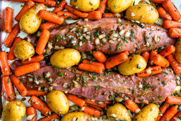 Closeup Overhead View of Marinated Pork Tenderloins with Vegetables on a Sheet Pan: Raw pork roast...