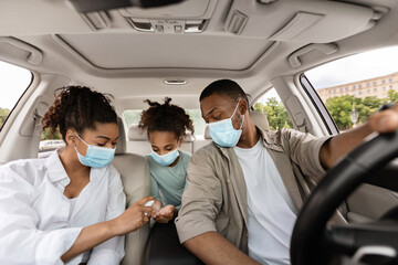 Black Family Spraying Sanitizer On Hands In Car
