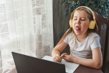 Speech training concept. Little girl uses a laptop to study at home with a teacher, a speech therapist. Distance learning. A kid doing exercises for correct pronunciation. - obrazy, fototapety, plakaty