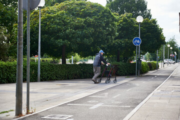 an older man walks with the help of a walker