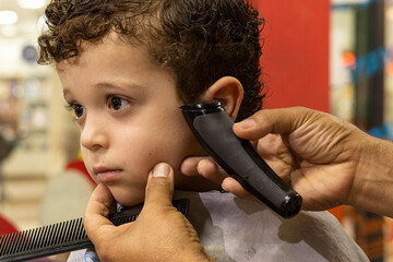 barber cutting a child's hair with curls