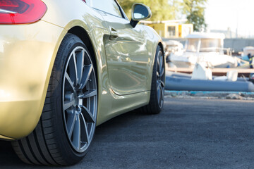 The golden car. Advertising concept. Car wheels close-up on asphalt background. Beautiful...