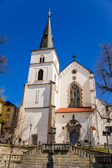Litomysl, Czech Republic, 17 April 2022: gothic medieval church of the Exaltation of the Holy Cross with tower at sunny summer day, Chapel of St. Marquette, stone statues