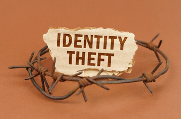 On a brown surface, barbed wire and a cardboard sign with the inscription - Identity theft
