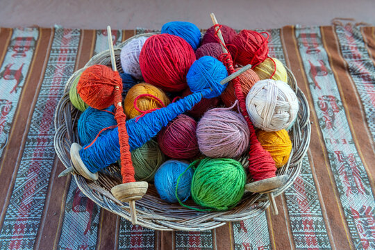 Top view of a basket with alpaca wool yarn balls and spinning spindles in a textile production center in Cusco, Peru.
