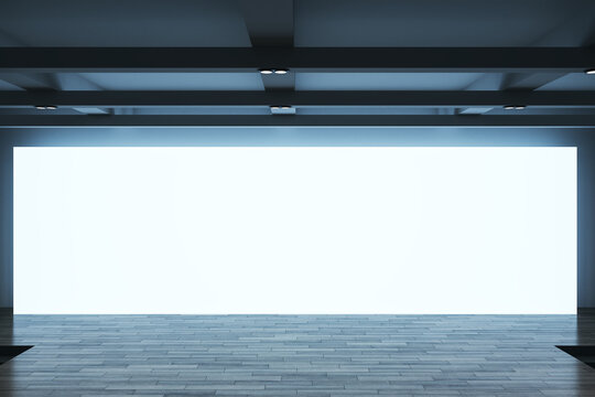 Front view on big blank white screen wall with place for your text or logo and blue backlit behind empty wooden stage in abstract hall. 3D rendering, mock up