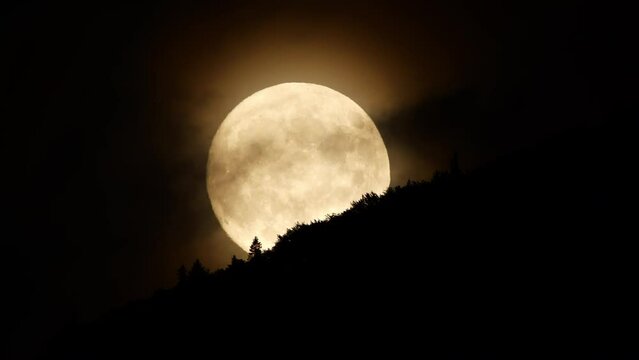 Moon with clouds at night sky over mountain forest, mystical and mystery huge moon nature Timelapse
