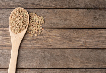 Fototapeta na wymiar Raw lentils on a spoon over wooden table with copy space