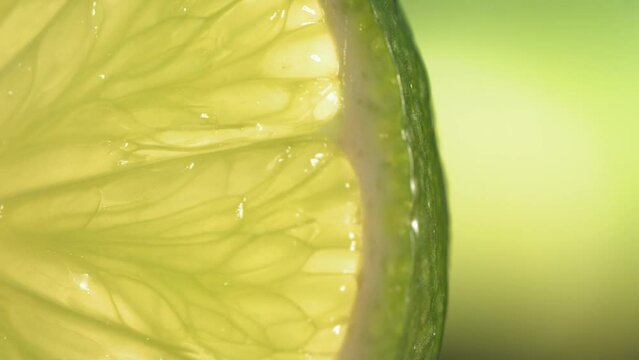 Drop of water flows down the surface of a ripe juicy Lime slice. Slow Motion 4K