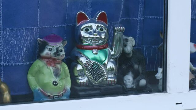 Bobruisk, Belarus - June 18, 2022: There are old toys on the window. Among the toys on the window is a cat waving its paw.