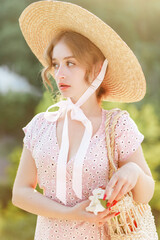 Close up portrait of a sweet blonde in a straw hat at the sunset