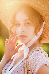 Close up portrait of a beautiful blonde in a straw hat at the sunset