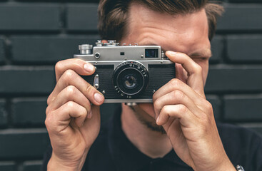 A young man takes a photo with a vintage film camera.