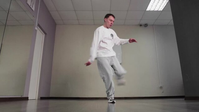 Down view of young guy breakdancer dances hip hop on floor in studio. Handsome guy performing dancing movements on floor