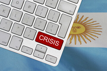 White computer keyboard with red button with word of crisis on Argentina flag background. Global...