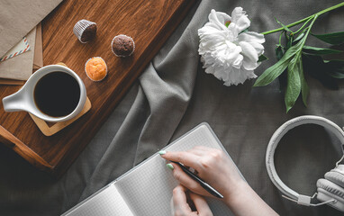 Flat lay composition in bed, with coffee and notepad.