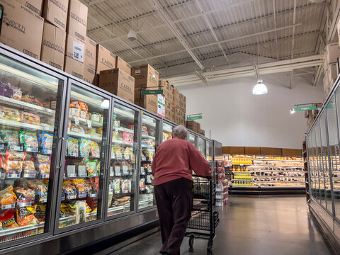 Mill Creek, WA USA - Circa May 2022: Angled View Of An Older Woman In A Pink Hoodie Shopping In The Frozen Food Section Of A Town And Country Market.