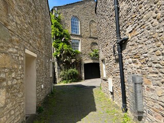 Small stone cobbled lane, leading past old cottages into a courtyard, with roses and plants, in the village of, Gargrave, UK