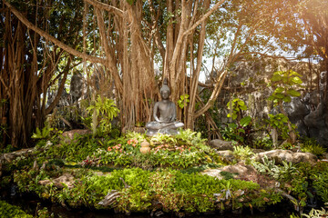 Estatua de buda meditando en jardín natural, dentro de templo budista tailandes