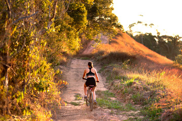 Woman riding a mountain bike up a trail in the afternoon. © Marcio
