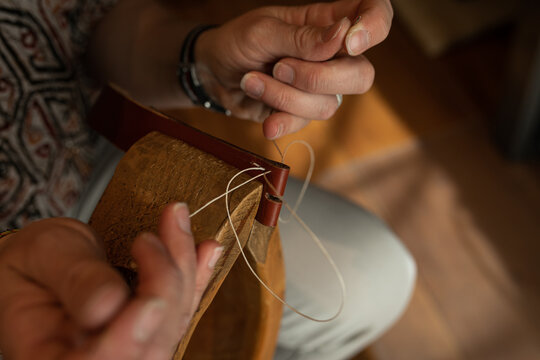 Handmade. the girl sews a leather belt in the workshop. Wooden machine. Atmospheric photo. Close up