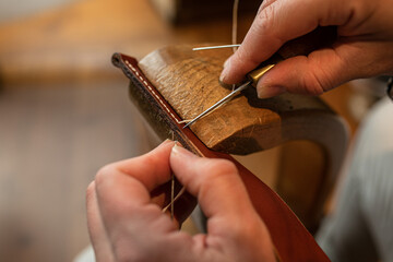 Handmade. the girl sews a leather belt in the workshop. Wooden machine. Atmospheric photo. Close up - Powered by Adobe