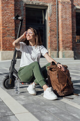 Young woman in white sneakers is sitting on electric scooter