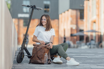 Young woman in white sneakers is sitting on electric scooter