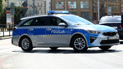 Radiowóz polskiej policji jedzie alarmowo ulicami miasta. 