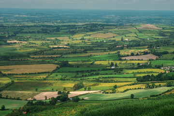 Obraz premium Farmland with green grass field in county Tipperary, Ireland. Stunning Irish landscape scene. Blue cloudy sky. View from a high point.