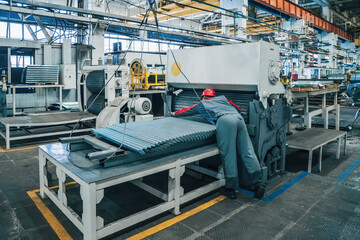 Metal sheet forming machine production line at metalwork factory controlled by technician worker.