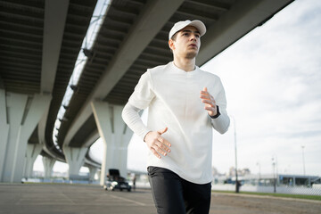 Fototapeta premium Runner male athlete active exercises, uses a fitness watch on his arm. Outdoor training