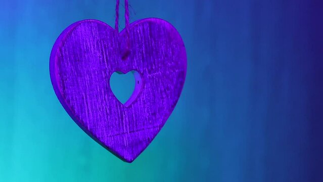 Wooden heart suspended by string, lit by multi-colour flashing light