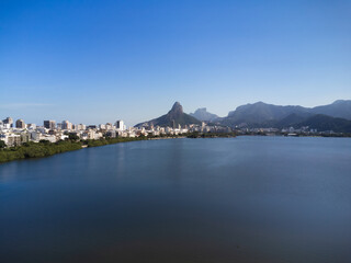 Fototapeta premium Aerial view of Rodrigo de Freitas Lagoon, south zone of Rio de Janeiro, Brazil. In the background, the beaches of Ipanema and Leblon and Morro Dois Irmãos. Sunny day. Buildings around. Drone photo
