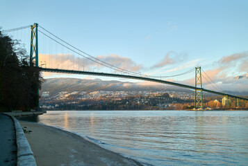 Fototapeta premium Lions Gate Bridge Burrard Inlet Winter. The Stanley Park seawall and the Lions Gate Bridge over Burrard Inlet. North Vancouver in the background.
