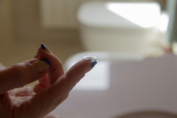 Image of a woman's hand holding a contact lens on her finger