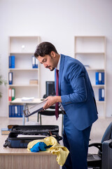 Young male employee preparing for trip at workplace