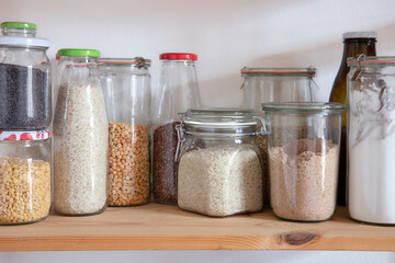Kitchen shelf with glass Jars full of dried Food. Eco friendly food storage.