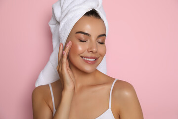 Beautiful young woman with towel on head against pink background