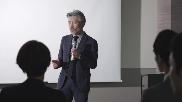 セミナーでプレゼンを行うミドルビジネスマン