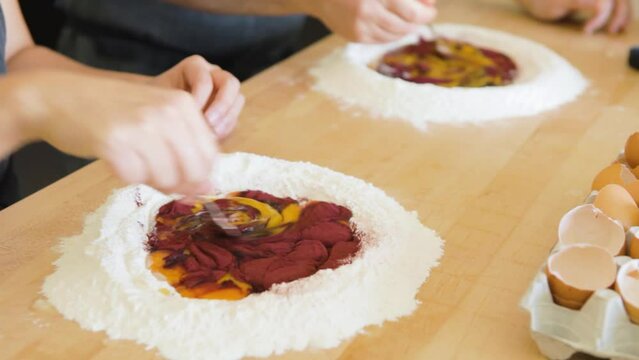 Couple stirring flour and egg yolks for a couple's pasta cooking class