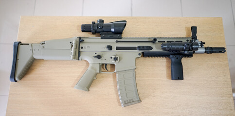 Scar-L automatic rifle at table. Weapons for police, special forces and the army. Automatic carbine with mechanical sights. Assault rifle on wooden table.