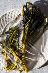 Asparagus wrapped in plastic on a plate 