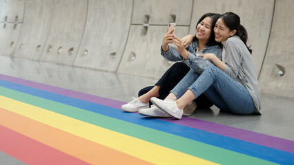 Young adult queer lover transgender asia two gay people fun happy enjoy selfie digital photo shoot at colorful floor. LGBT LGBTQIA color bisexual family festival hug love smile at city street town. © ChayTee